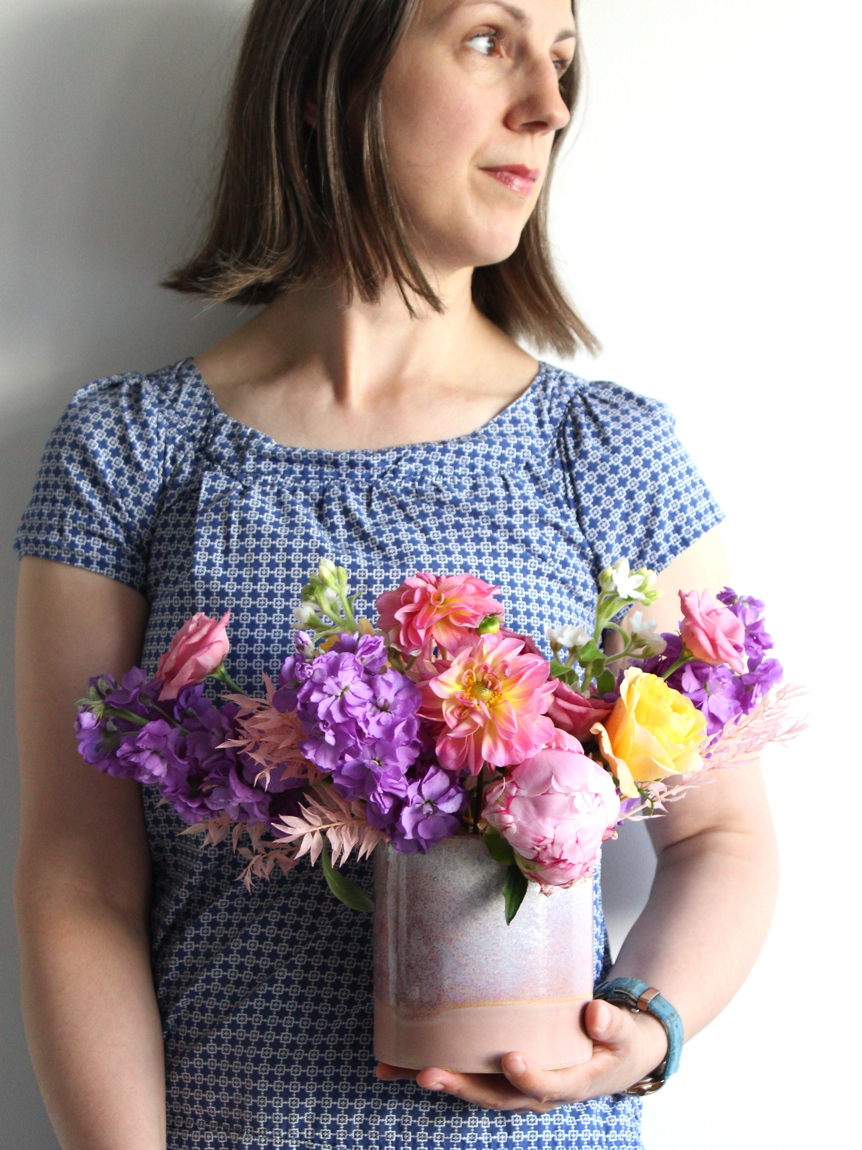 Seasonal flowers are arranged in a lavender ceramic vase ready for celebrating any special occasion.