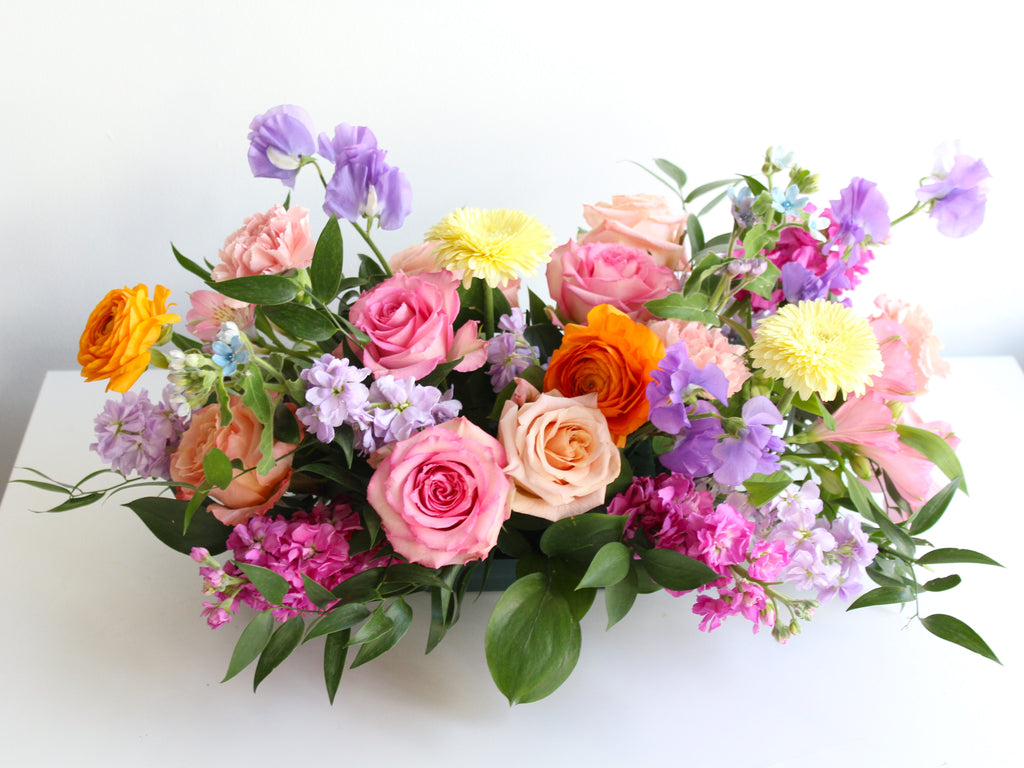 A colorful mix of garden flowers arranged in a low dish makes a beautiful table centerpiece arrangement ready for a dinner party of celebration.