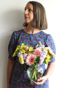 A glass vase filled with flowers in pastel tones being held by Toronto florist Periwinkle Flowers, perfect for birthdays and get well soons